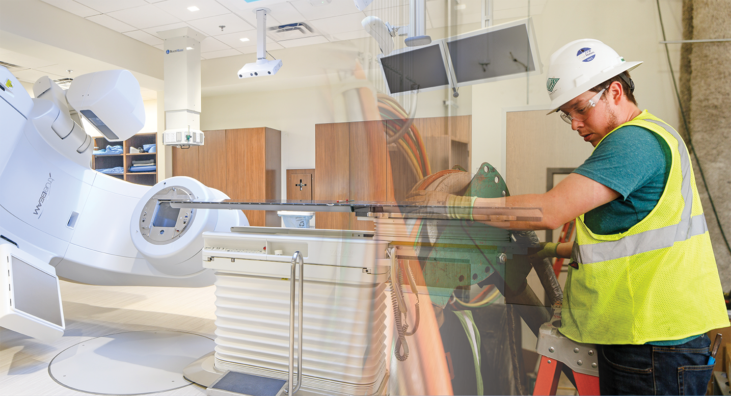 Composite image showing a modern medical treatment room with large radiotherapy equipment blended with a construction worker wearing safety gear and operating tools.