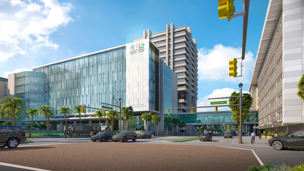 Street view of a large building, cars in the foreground with traffic lights